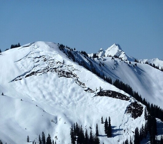 Montagne enneigée avec rupture en surface du manteau neigeux typique d’un départ d’avalanche en plaques.