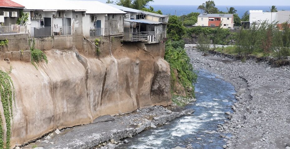 Maisons construites en bordure de ravin fortement érodé dans les Outre-mer.