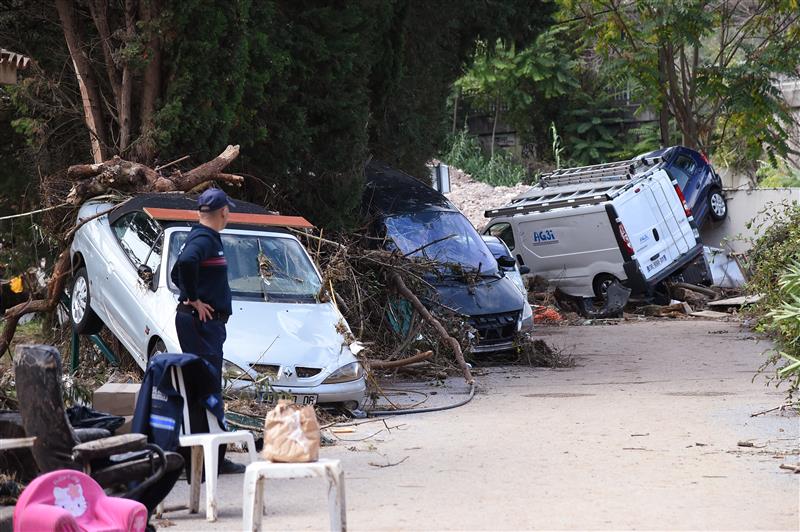 Voitures et mobilier endommagés par les inondations dans le sud-est de la France en 2015, avec un pompier observant les dégâts.